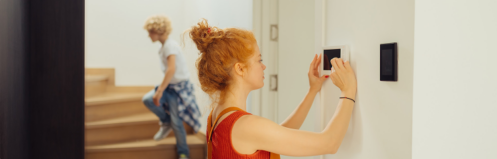 woman adjusting the thermostat in her home