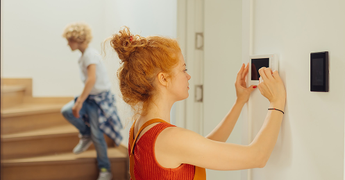 woman adjusting the thermostat in her home